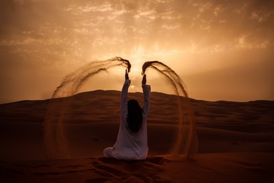 黄金时期坐在沙漠上玩沙子的女人